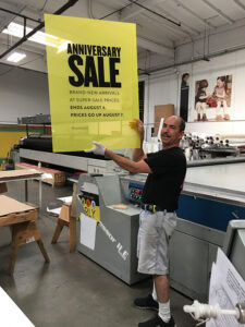 large format screenprinted acrylic retail sign being produced in print shop